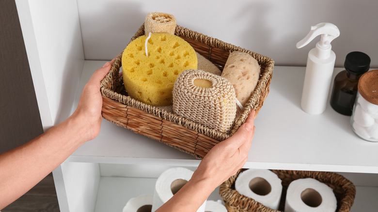 woman placing woven storage basket on bathroom shelf