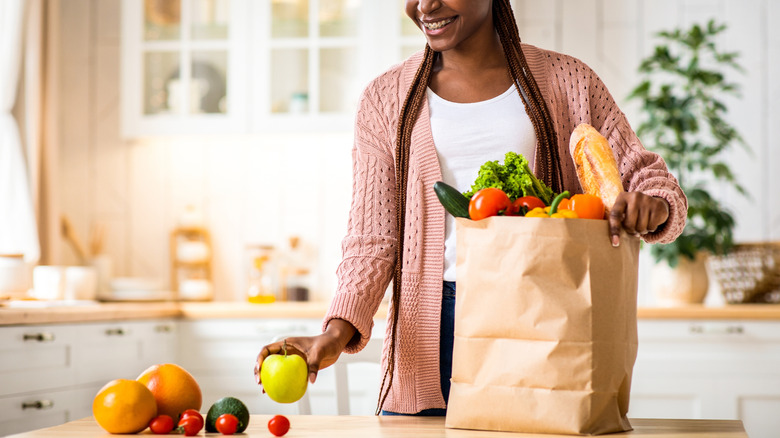 A person unloading fresh fruit from a grocery bag in the kitchen
