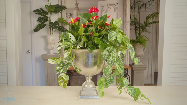 A vintage silver ice bucket filled with plants and flowers