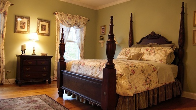 Heavy carved wood four poster bed with flowered bedding