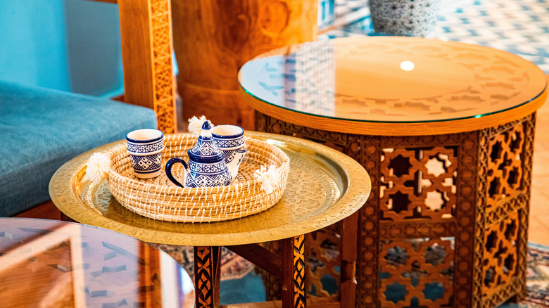 A Moroccan tray table with Moroccan cups and teapot on top of it.