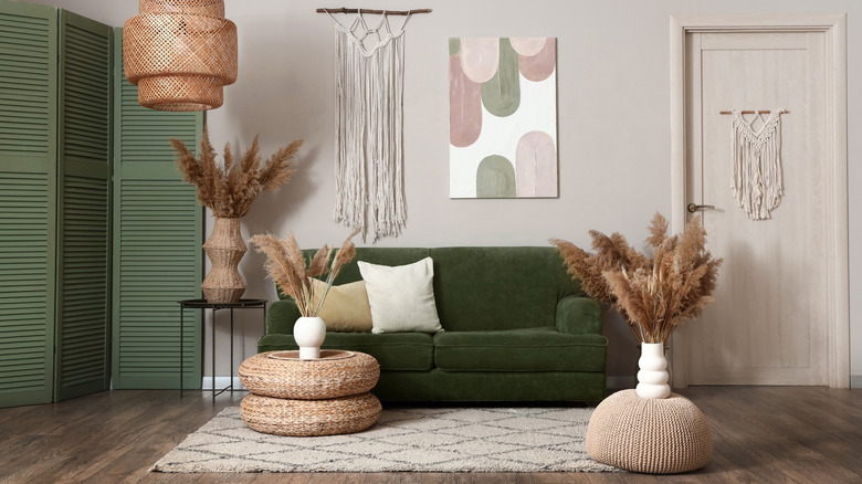 A living room with green sofa and two poufs used as tables.
