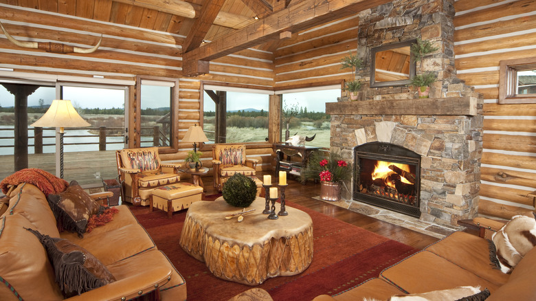 A rustic bain living room with tree stump table, open fire and brown leather sofas.