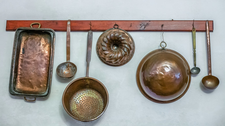 A rack of copper kitchen utensils and pans.