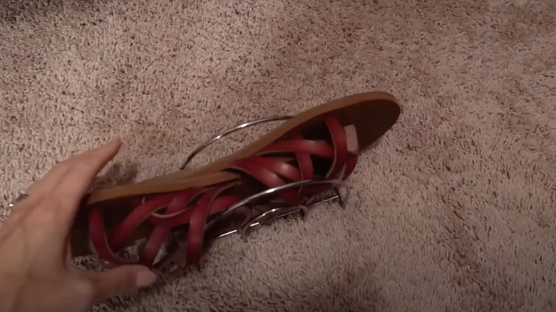 A woman using a wire napkin holder as a shoe organizer