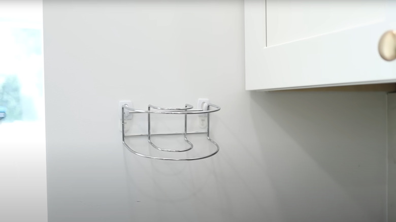 A wire napkin holder attached to a wall with plastic hooks
