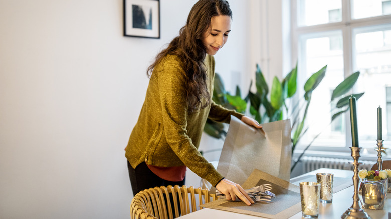Woman arranging placemats on a table