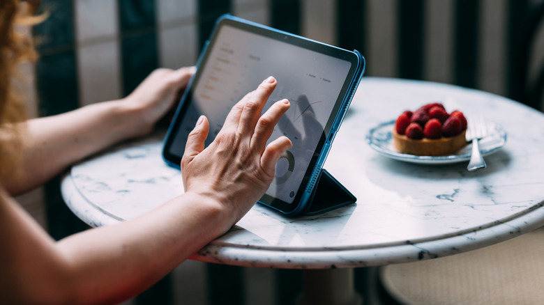 Woman using tablet at table with berry dessert