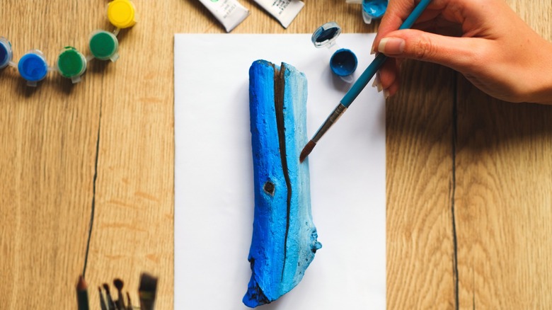 Person painting tree log blue