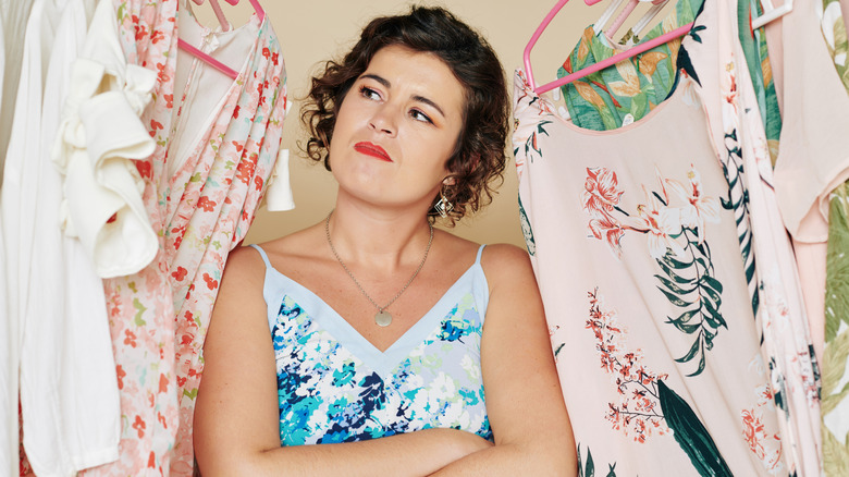 brunette woman considering her clothes as if trying to decide what to keep