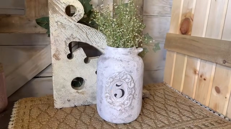 A pickle jar has been transformed into a vintage crock with air-dry clay and other craft materials.