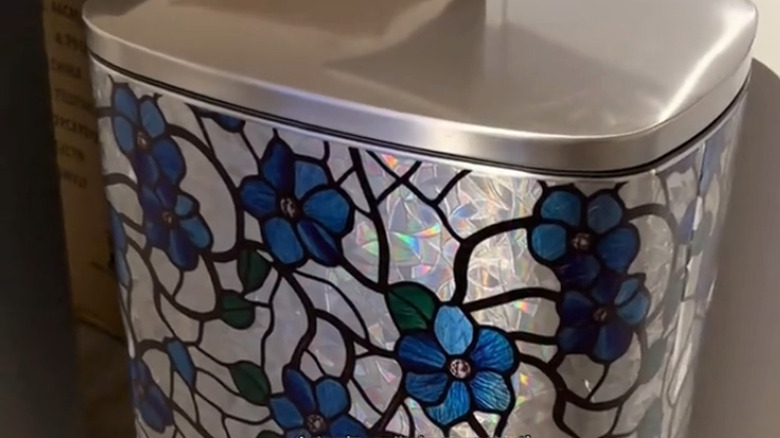 As seen in Emilee Benzo's TikTok video, this trash can has been upgraded with a blue and silver stained glass window cling