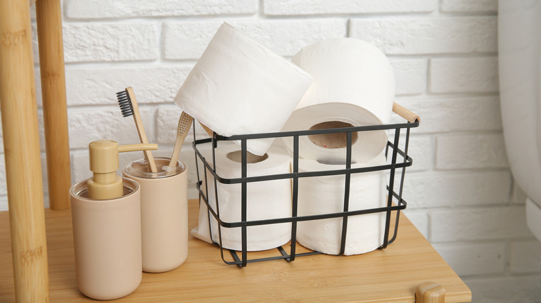 Toilet paper rolls in wire basket near toothbrush holder and soap