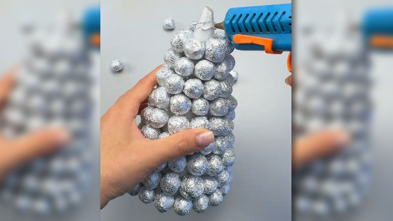 Someone crafting a foil ball tree with a hot glue gun