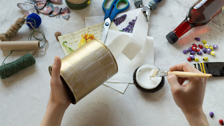 A person decorates a tin can.