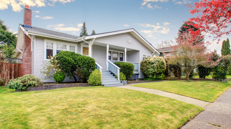 The front yard of a house with green grass and bushes