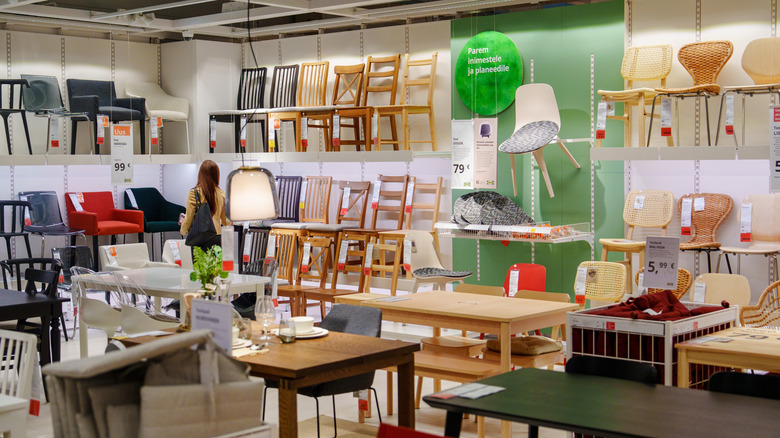 Woman shopping in IKEA, wooden chairs and tables on display