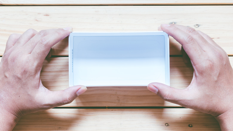 A person holds a smartphone box with two hands