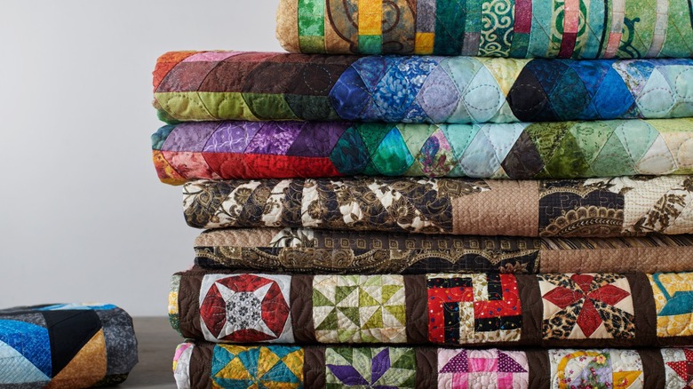 A stack of old quilts with bold colors and designs.