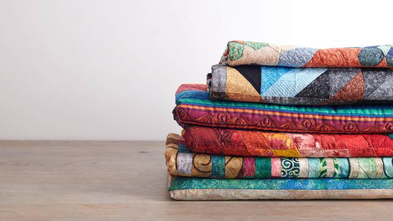 A stack of old quilts with bold colors and designs.