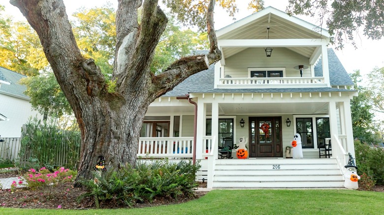 House with Halloween decorations and large tree in front yard