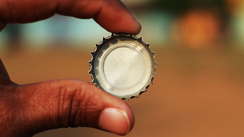 A hand holding a bottle cap