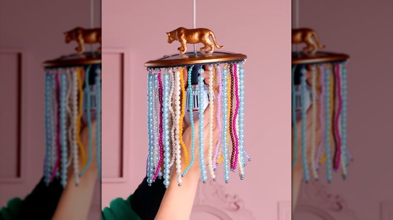 The lid of a pot is decorated with a toy tiger, gold paint, and beaded fringe, and hung up as a pendant light.