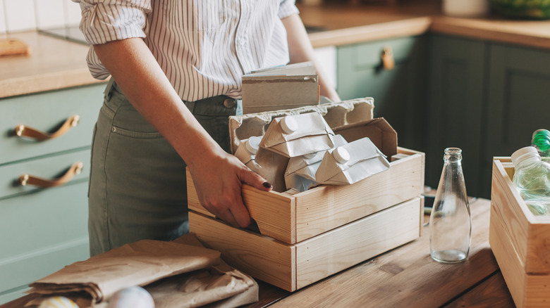 Woman sorting kitchen items into wooden storage bins