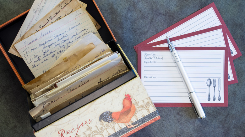 An old-fashioned recipe box is full of recipe cards, with blank cards next to it
