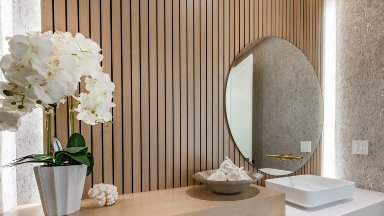Wood slat accent wall behind a round mirror
