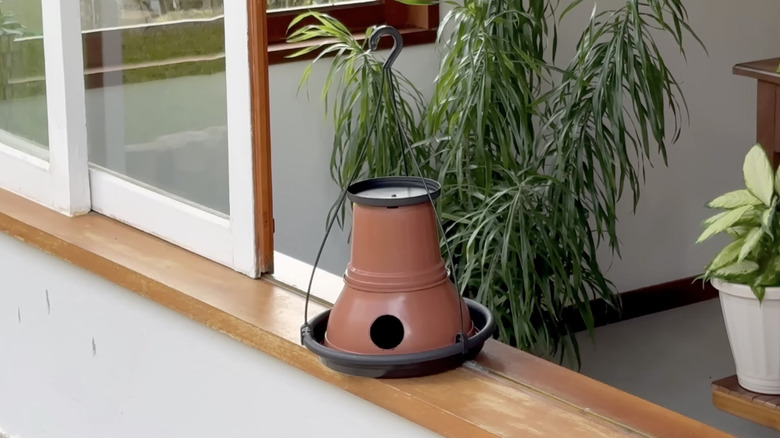 A hanging DIY combination bird feeder and house made from old nursery pot parts