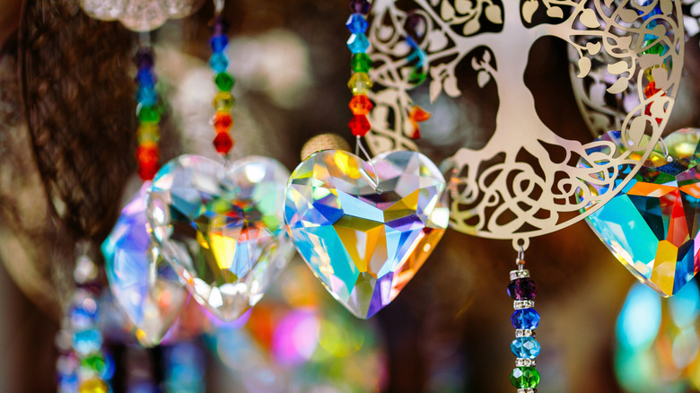 A suncatcher made with heart-shaped crystals, colorful beads, and a large metal charm.