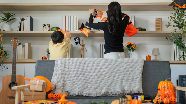A parent and child work together to decorate a room for Halloween