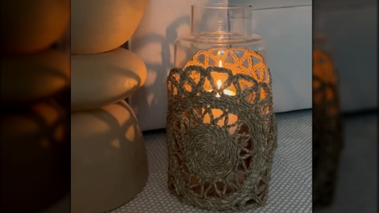 A glass candle jar is decorated with a sleeve made from two placemats sewn together