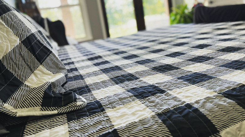 A bed and pillows with a buffalo plaid bed spread