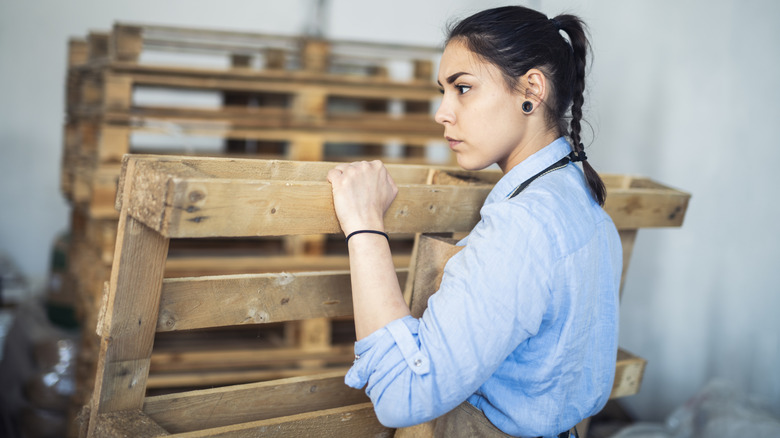 woman picking up a wooden pallet
