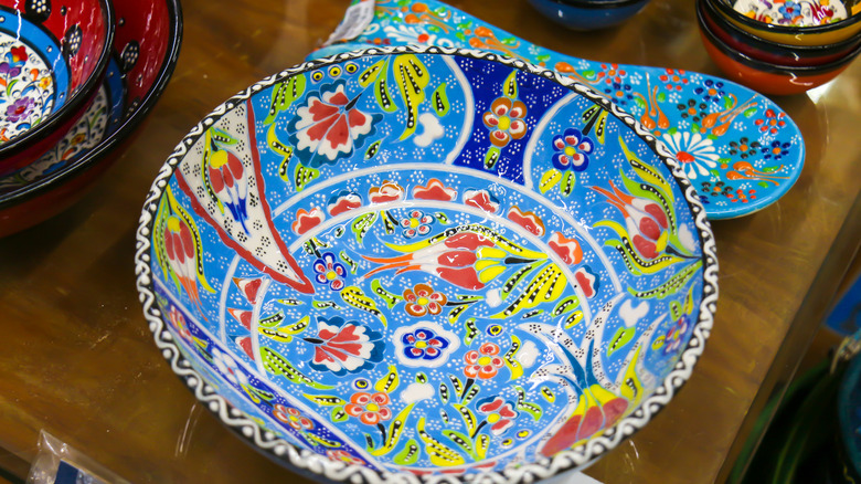 A colorful serving bowl in shades of blue, red, and yellow is displayed with other colorful housewares.