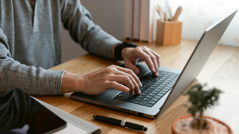 A person typing on a laptop at a desk