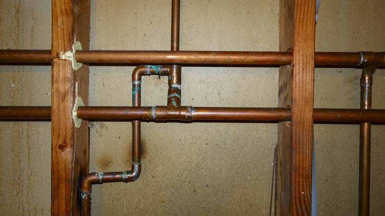 A concrete wall with wood beams and copper plumbing.