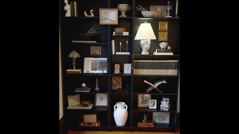 Black bookshelf with mounted photos and decor