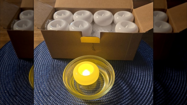 Water-activated decorative faux candles in a box with one lamp in a bowl of water.