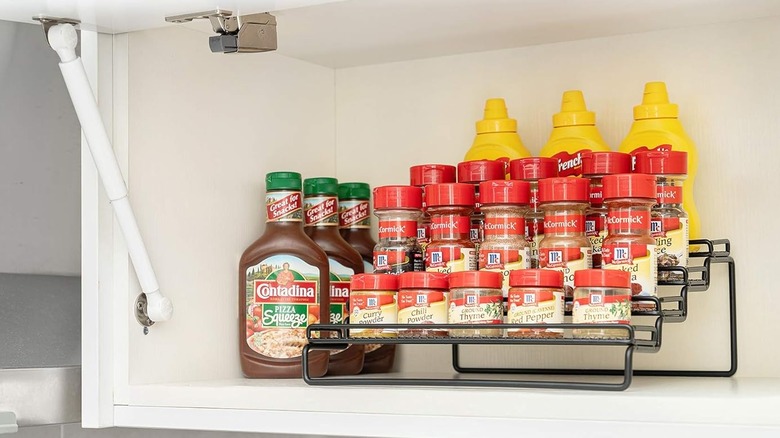 A black metal spice rack in a white cabinet