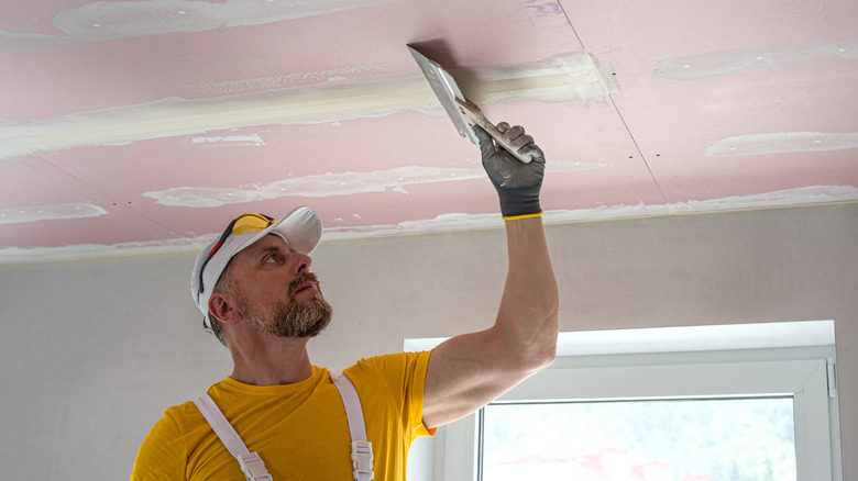 Contractor installing drywall on ceiling