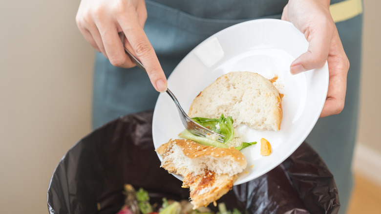 Person throwing leftover food into trash bin