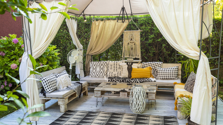 Black and white patio space with outdoor curtains and patterned pillows