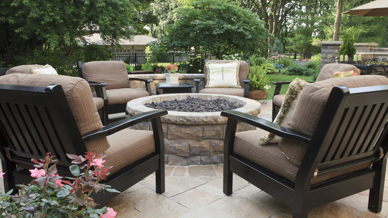 Outdoor space with comfy chairs around a stone firepit