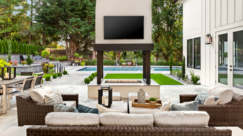 Outdoor living area with couches, chairs and mounted TV