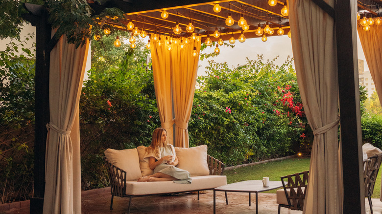 Covered patio space with outdoor curtains and white furniture