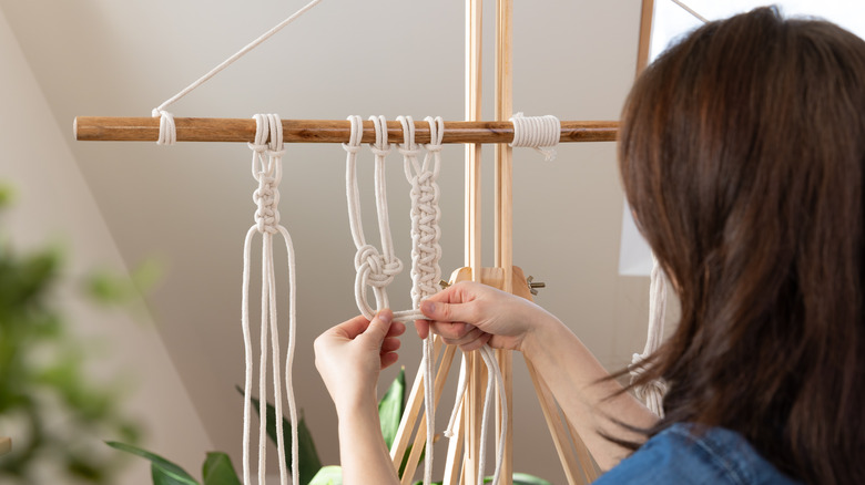 person making macrame on dowel