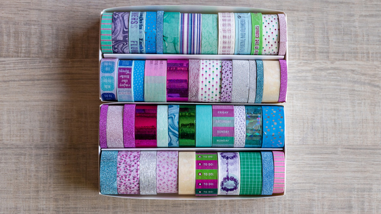 Box of colorfully-printed washi tape on a wood surface